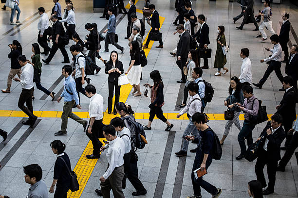 Japanese woman talking on the mobile phone surrounded by commuters walking to work.