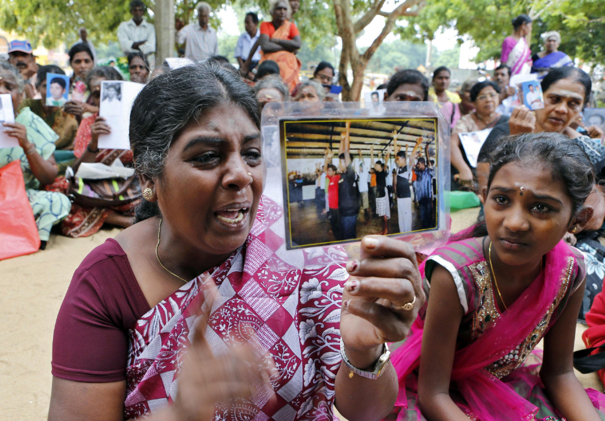 NOV. 15, 2013 PHOTO In this Nov. 15, 2013 photo, Sri Lankan ethnic Tamil woman Balendran Jeyakumari, left, weeps holding a photograph of her missing son as her daughter Vithushaini sits beside her during a protest by the family members of missing persons coinciding with the visit of British Prime Minister David Cameron in Jaffna, Sri Lanka. Sri Lanka’s police have arrested Jeyakumari and her 13-year-old daughter, in what human rights activists say is part of continuing efforts to intimidate families of the country’s civil war-missing into silence. Jeyakumari had been vocal in calling for the release of her 15-year-old son, a child recruit of the Tamil Tiger rebels whom she had handed to the military as fighting ended in 2009.  (AP Photo/Eranga Jayawardena)en
