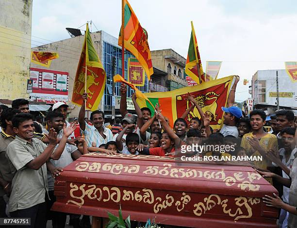 Sri Lankan children cheer behind a mock coffin of the dead Tamil Tiger leader Velupillai Prabhakaran to celebrate the country's military victory in Colombo on May 18, 2009.  The entire Tamil Tiger leadership including rebel leader Velupillai Prabhakaran has been wiped out by government troops, Sri Lankan state television announced.  AFP PHOTO/ROSLAN RAHMAN (Photo credit should read ROSLAN RAHMAN/AFP via Getty Images)