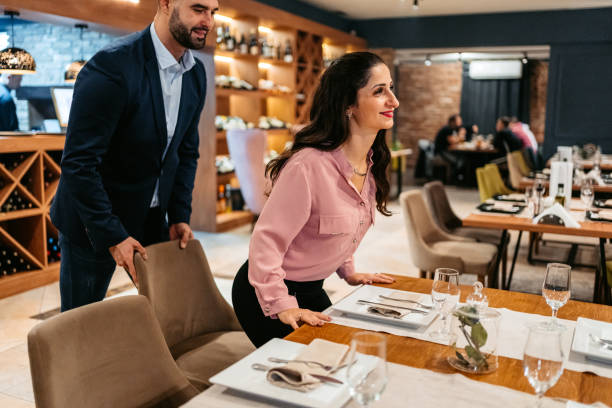 Mid adult man pulling the chair for his wife at the restaurant.