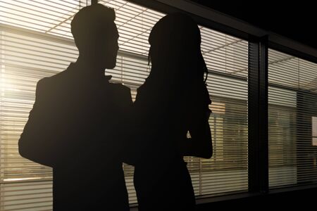 139124781 concept image of romance at work silhouettes of a woman and a man hugging each other in a dark corpo